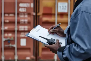 Worker writing on a clipboard at a logistics facility